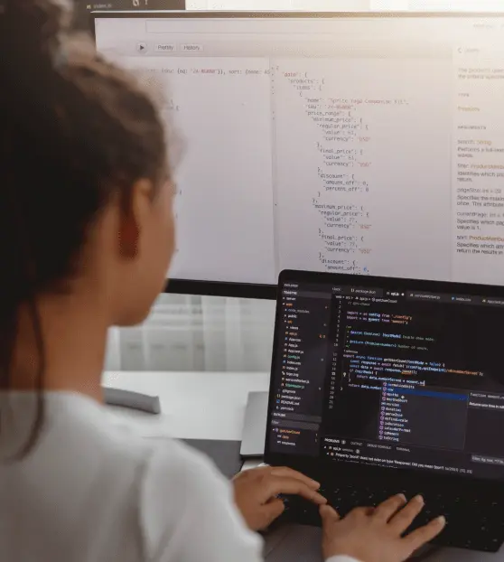 Programmer at Workstation with Dual Screens for Cms Development Person coding Cms Development Project on a laptop with large monitor display
