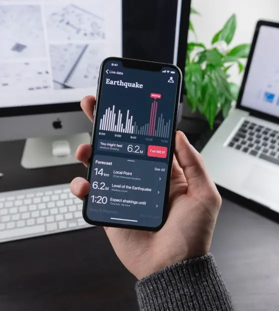 Smartphone with Earthquake Monitoring App Hand holding smartphone displaying earthquake data